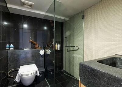 Modern bathroom with glass shower enclosure and dark tile accents