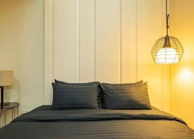 Modern bedroom with dark bedding and hanging light