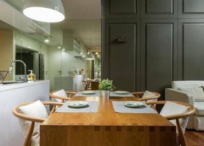 Modern dining area with wooden table and chairs, adjacent to kitchen and living space