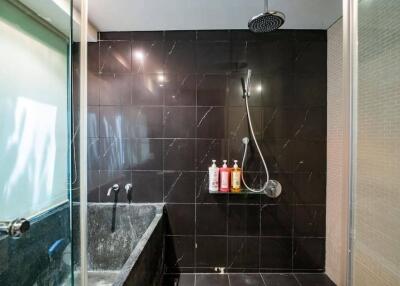 Modern bathroom with black tiles, bathtub, and shower