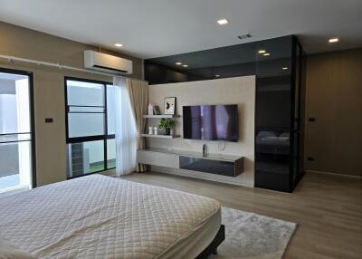 Modern bedroom with large window, air conditioning, and wall-mounted TV