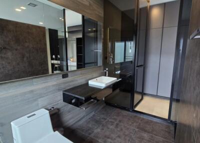 Modern bathroom with dark tiles, glass shower, and floating vanity