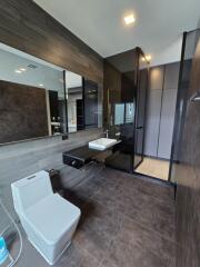 Modern bathroom with dark tiles, glass shower, and floating vanity