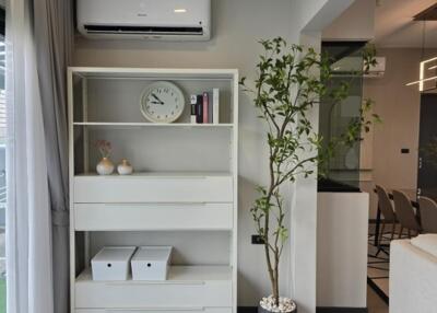 Modern living room with bookshelf, air conditioner, and indoor plant