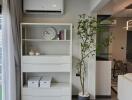 Modern living room with bookshelf, air conditioner, and indoor plant