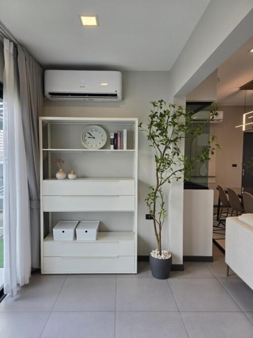 Modern living room with bookshelf, air conditioner, and indoor plant