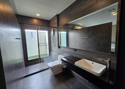 Modern bathroom with large mirror, glass shower, and white fixtures