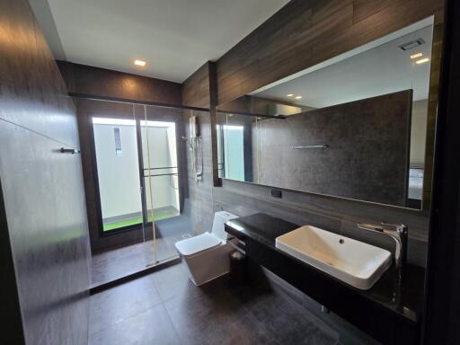 Modern bathroom with large mirror, glass shower, and white fixtures