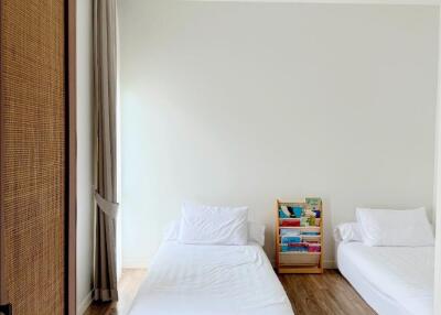 Minimalist bedroom with two single beds and a bookshelf