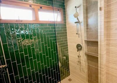 Modern bathroom with glass shower and green tiles