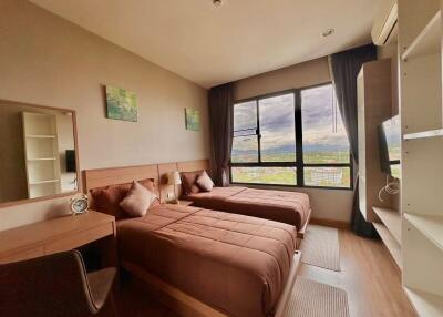 Spacious bedroom with twin beds, a desk, and a large window with a view