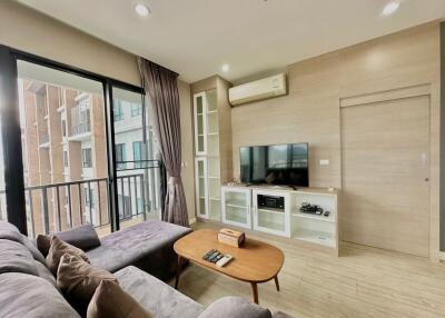 Modern living room with large windows, cozy gray sofa, and entertainment center