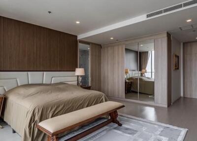 Modern bedroom with bed, nightstands, lamps, bench, and mirrored wardrobe