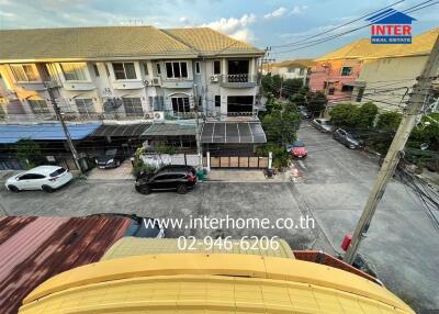 View of neighborhood from upper floor with houses, parked cars, and contact details for Inter Real Estate