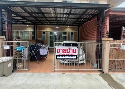 Front view of the house with car parking area and sale sign