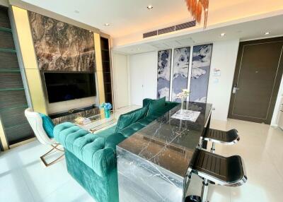 Modern living room with green sofa, marble accent wall, flat-screen TV, and breakfast bar