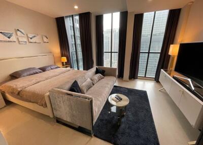 Modern bedroom with large windows, double bed, and seating area