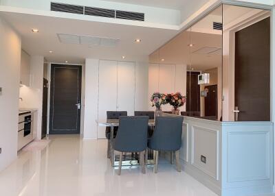 Modern dining area with a table set for four, adjacent to a sleek kitchen and living space.