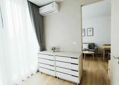 Room with white drawers and air conditioner leading to living area