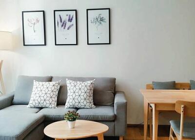 Modern living room with gray sofa, artwork on the wall, and a dining table