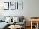 Modern living room with gray sofa, artwork on the wall, and a dining table