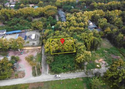 Aerial view of a plot of land surrounded by greenery and adjacent to a road