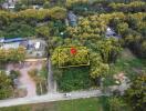 Aerial view of a plot of land surrounded by greenery and adjacent to a road