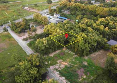 Aerial view of a plot of land marked with a pin in a forested area near roads.