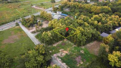 Aerial view of a plot of land marked with a pin in a forested area near roads.