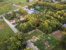 Aerial view of a plot of land marked with a pin in a forested area near roads.