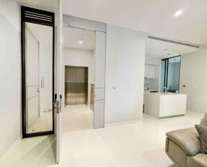 Spacious modern living area with white walls and adjacent kitchen