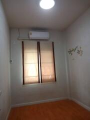 Simple bedroom with window, air conditioner, and wooden floor