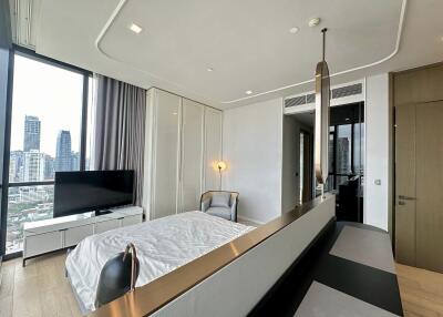 Modern bedroom with bed, large window, TV, and urban skyline view