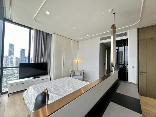 Modern bedroom with bed, large window, TV, and urban skyline view