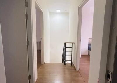 A bright hallway with wooden flooring and white walls, featuring doors leading to other rooms.