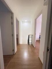 A bright hallway with wooden flooring and white walls, featuring doors leading to other rooms.