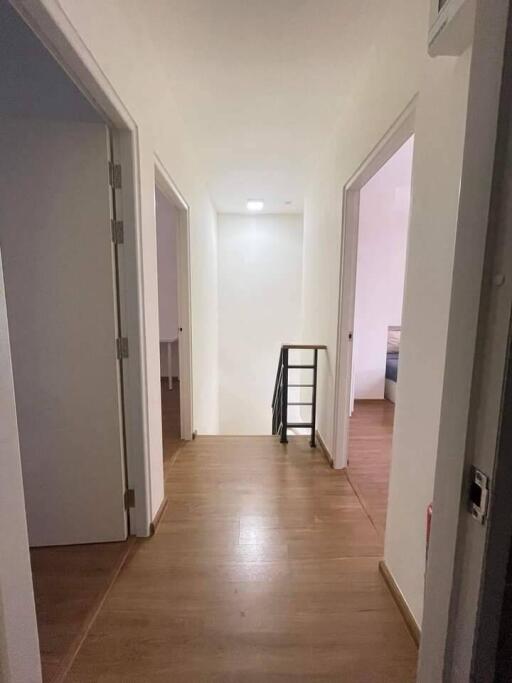 A bright hallway with wooden flooring and white walls, featuring doors leading to other rooms.