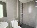 Modern bathroom with grey tiles, shower, and white fixtures