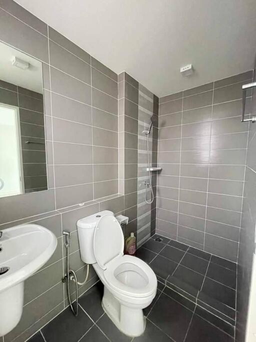 Modern bathroom with grey tiles, shower, and white fixtures