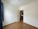 Simple empty bedroom with wooden floor and open door