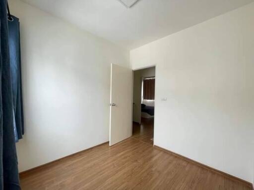 Simple empty bedroom with wooden floor and open door