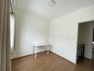 Basic bedroom with wood flooring and a small white desk