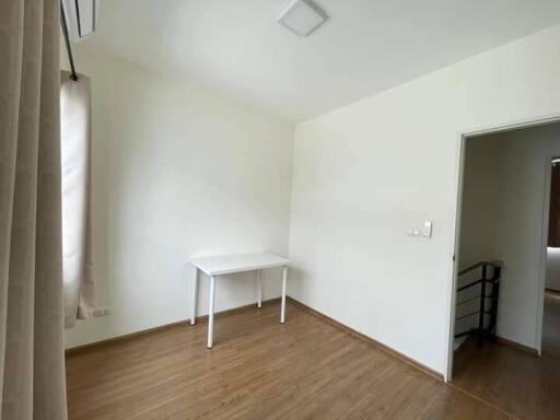 Basic bedroom with wood flooring and a small white desk