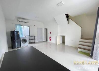 Main living area with a refrigerator, washing machine, staircase, and window