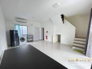 Main living area with a refrigerator, washing machine, staircase, and window