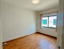 Empty bedroom with wooden floor and large window