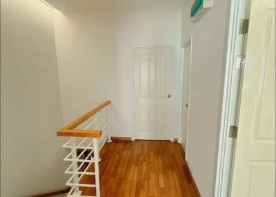 Well-lit hallway with wooden flooring and staircase