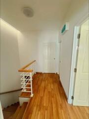 Well-lit hallway with wooden flooring and staircase