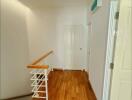 Well-lit hallway with wooden flooring and staircase