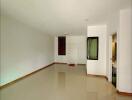 Spacious empty living room with glossy tiled floors and a doorway to additional rooms